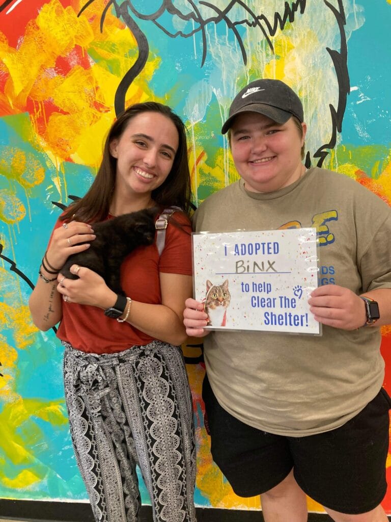 Couple with adopted pet and sign.