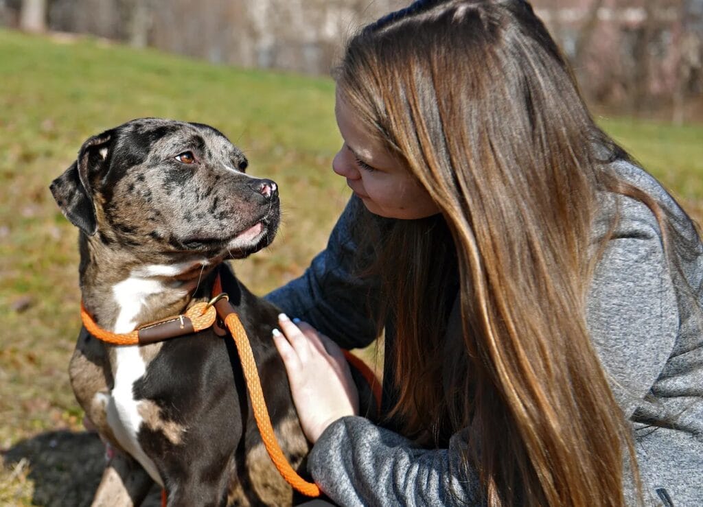 Woman interacting with a dog outdoors.